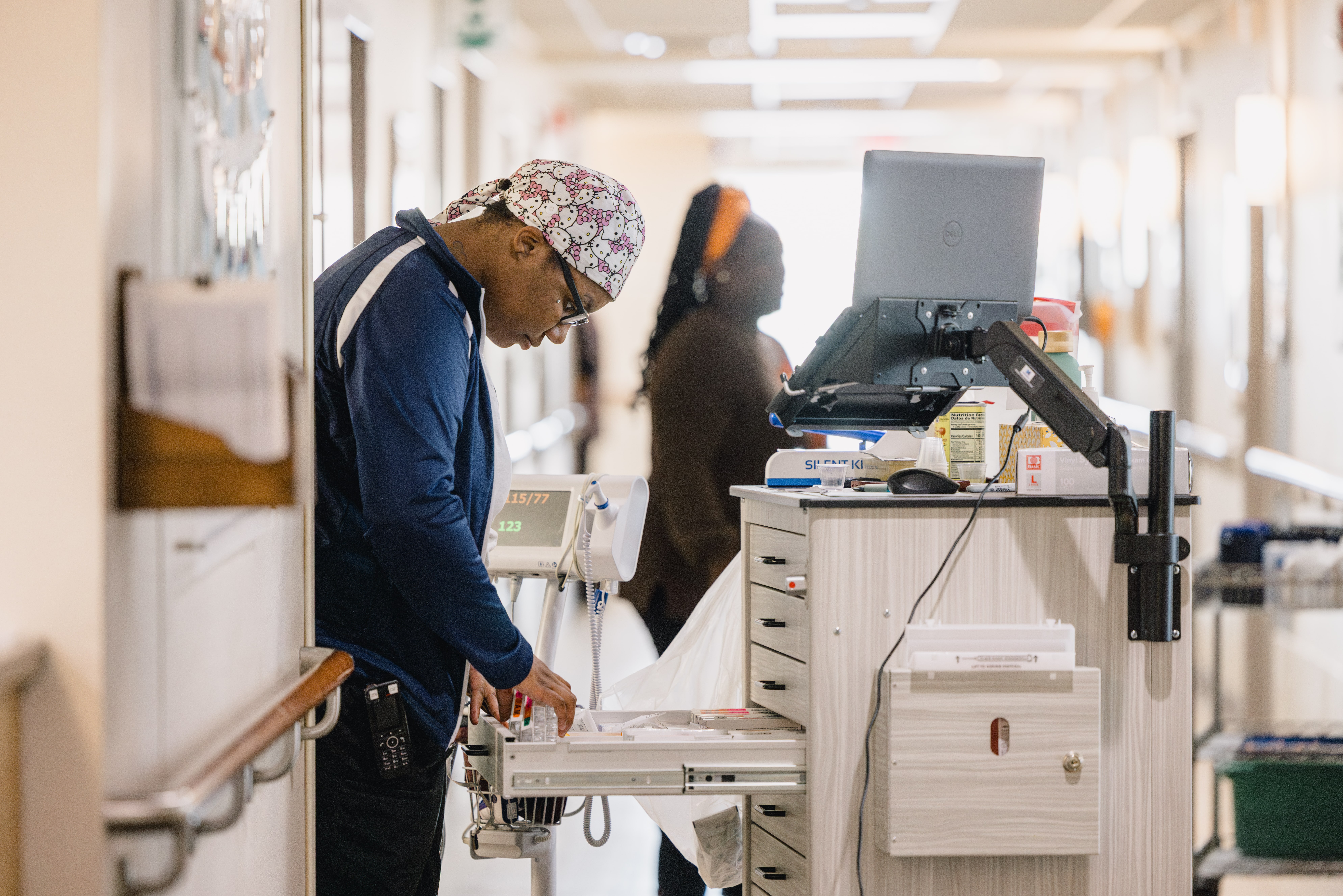 Mission Partners working in the hallway. One Mission Partner is sorting through medications.