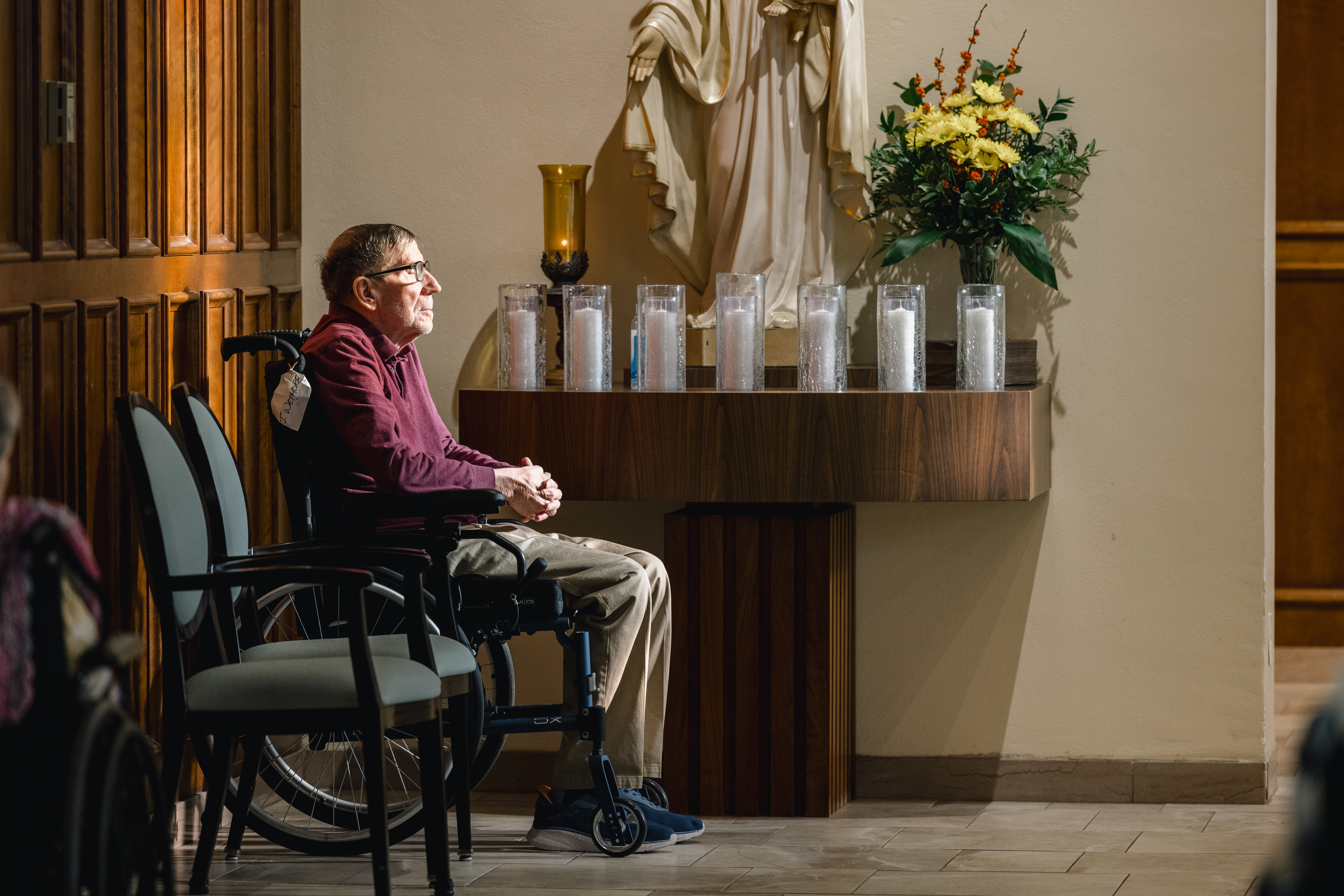 Resident in a wheelchair praying in the chapel