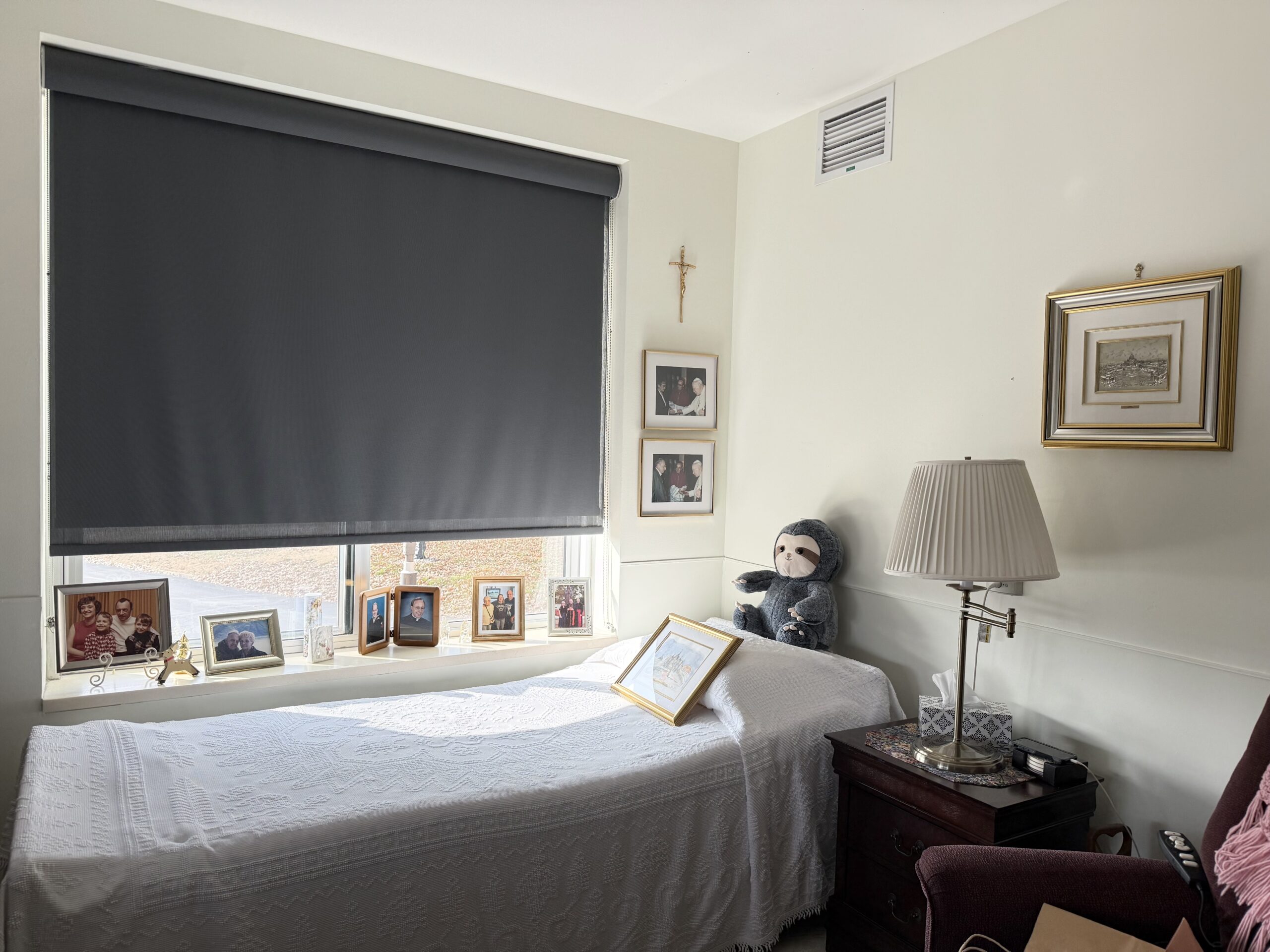 Resident's room. There are photos on the wall, a stuffed animal on the bed, and a lamp at the bedside.
