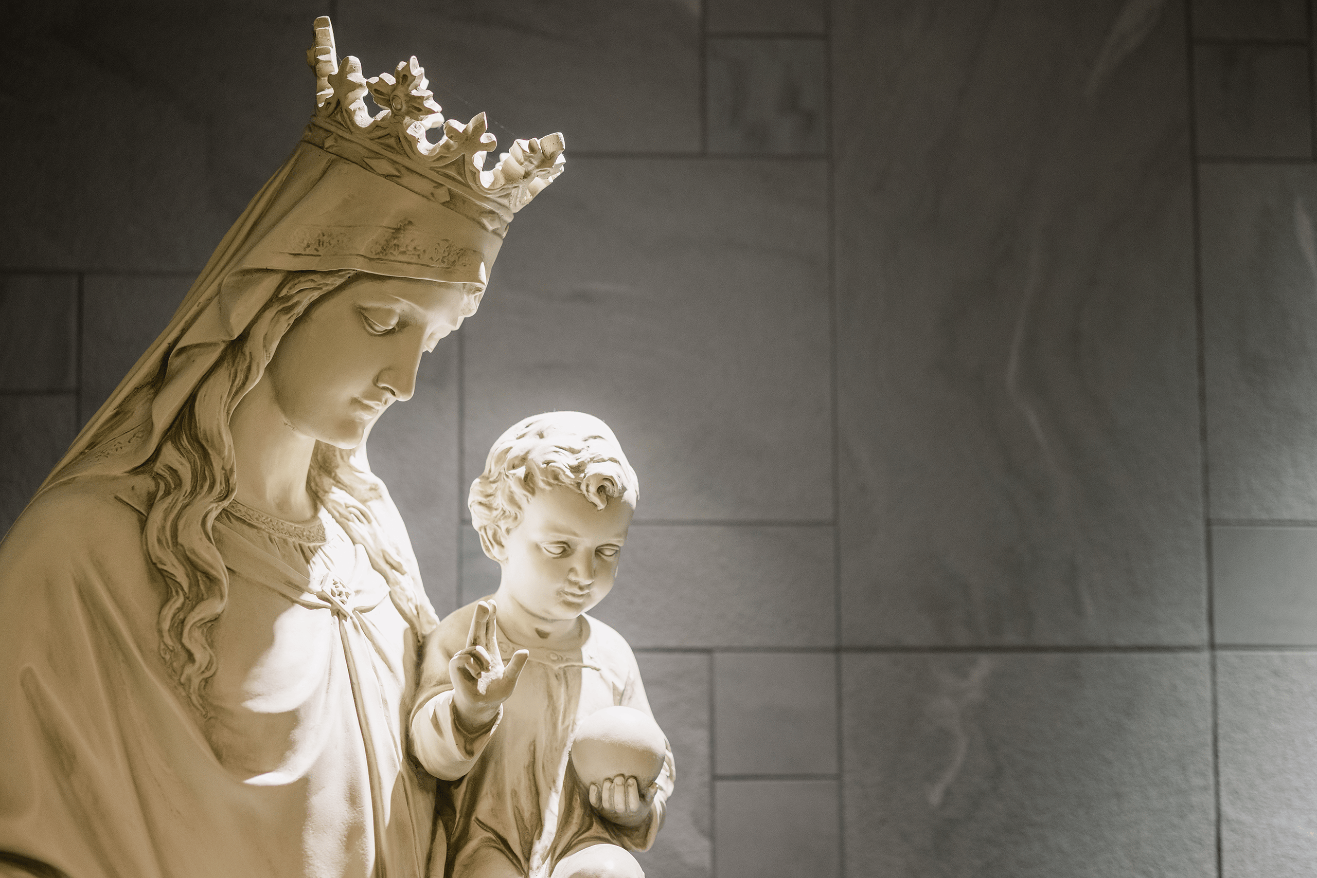 A statue of Mother of Good Counsel Home -- Mary with a crown holding baby Jesus who holds an orb in his hand and is giving a blessing.