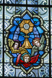 Stained glass window with the eucharist in a monstrance and three angels